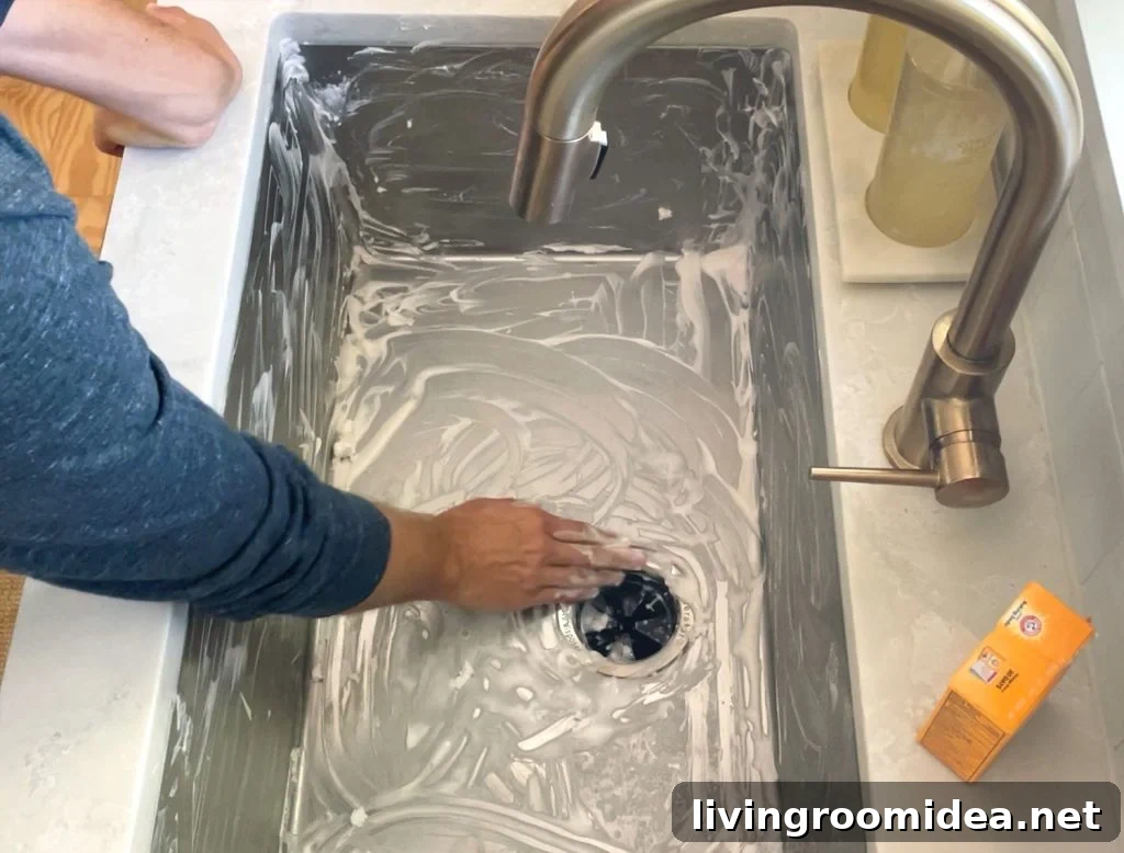 Hand scrubbing a stainless steel sink clean with baking soda