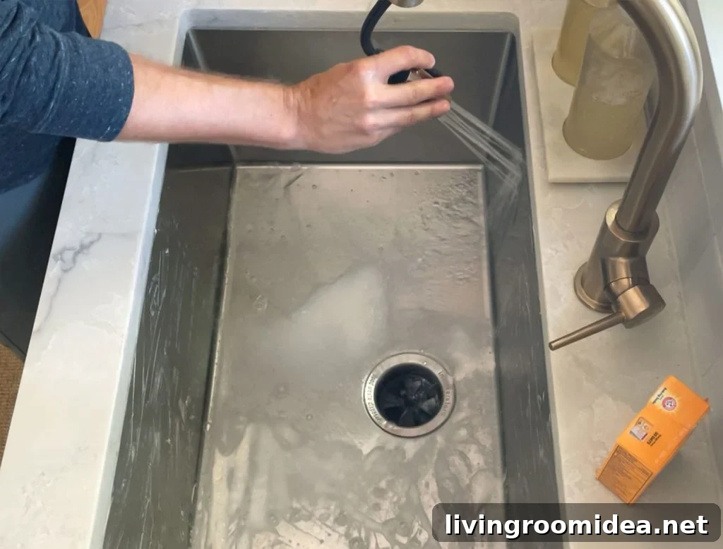 Rinsing stainless steel sink with warm water from faucet