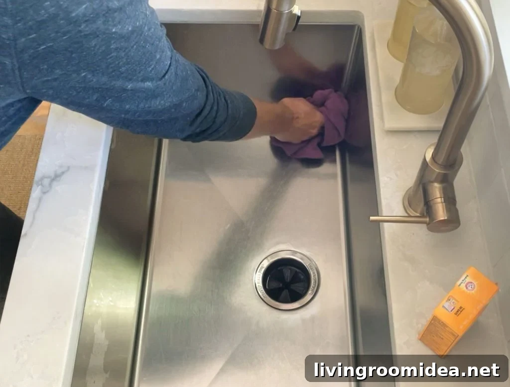 Buffing cleaned stainless steel sink dry with rag