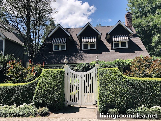 Charming white fence in hedge. Striped awnings.