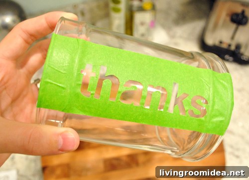 Painter tape THANKS stencil stuck to side of glass apothecary jar for Thanksgiving craft