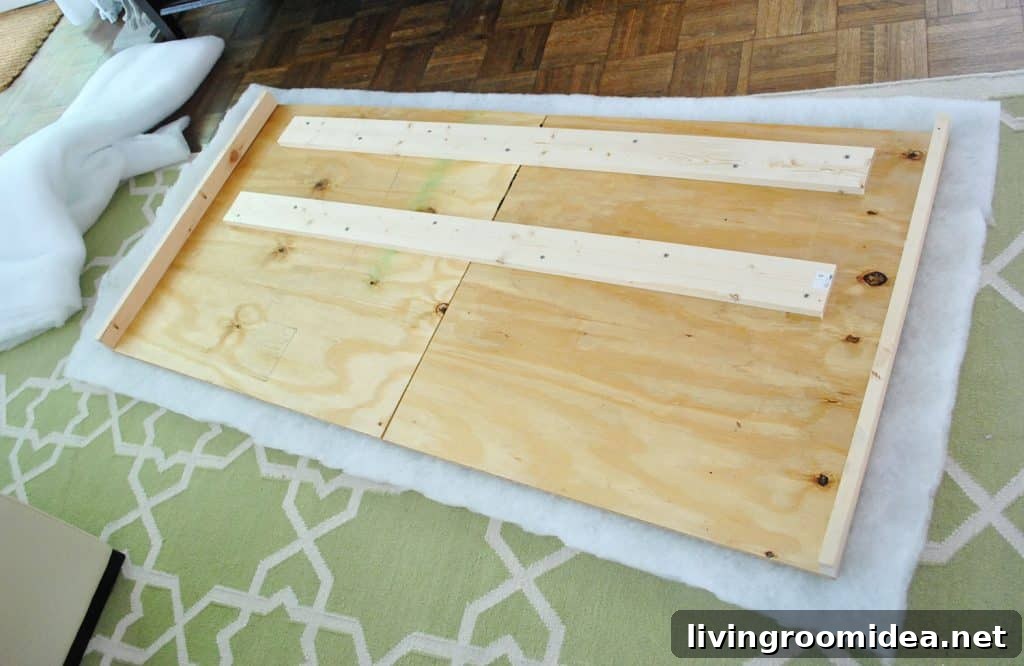 Layer of batting placed under DIY headboard wood frame