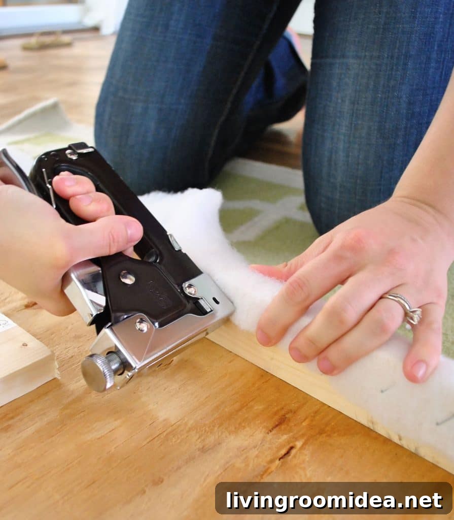 Using staple gun to attach batting to back of DIY upholstered fabric headboard