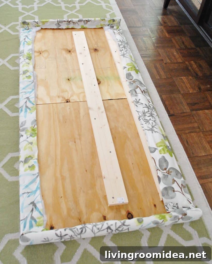 Fabric fully stapled along the backside of wooden headboard frame