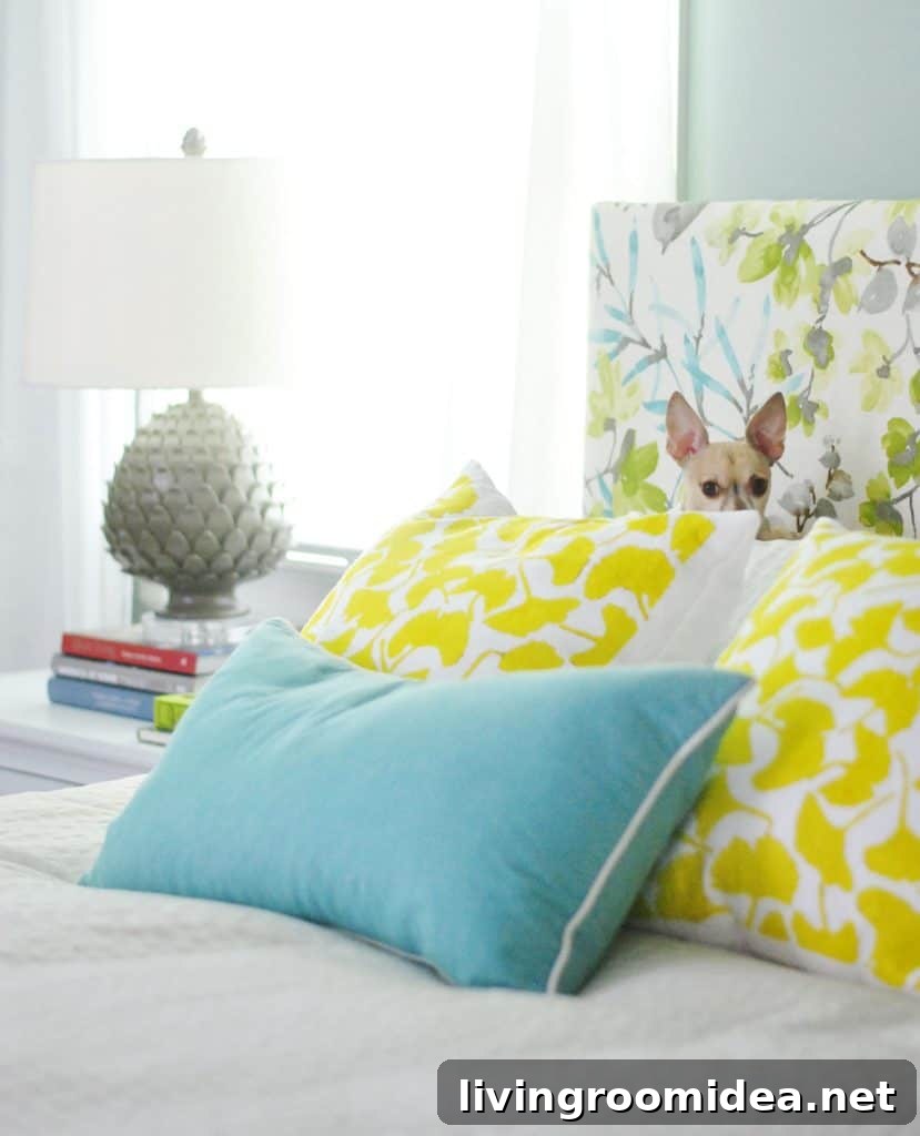 Chihuahua sitting on yellow gingko pillows against colorful upholstered DIY headboard
