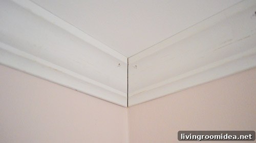 Corner of crown molding installed against ceiling with small seam at corner to be caulked