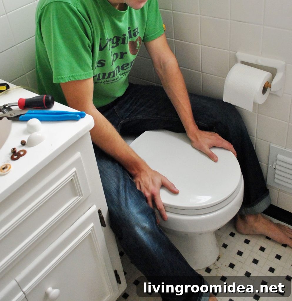 John Sitting On Back of Toilet Bowl To Press Into Place