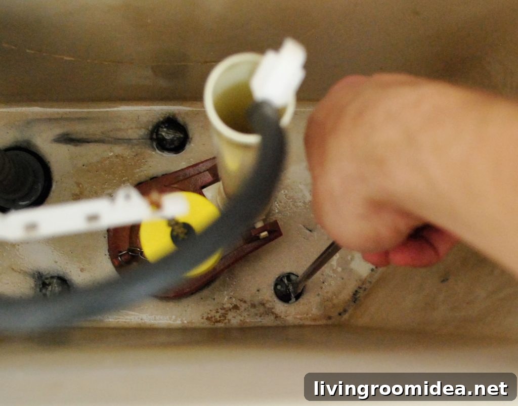 Hand With Screwdriver Adjusting Bolts In Toilet Tank