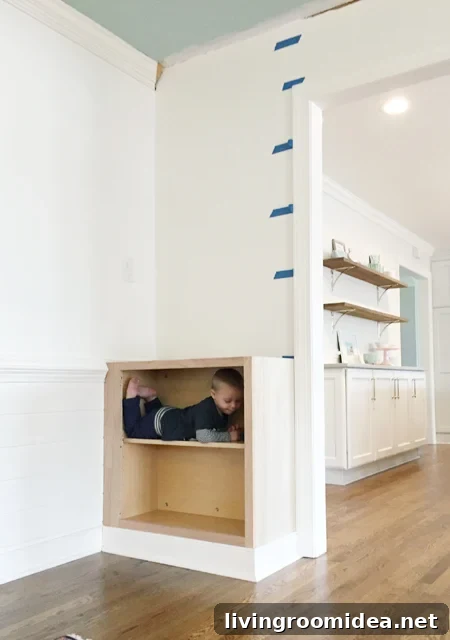 Base cabinet installed for built-in bookshelf with toddler inside