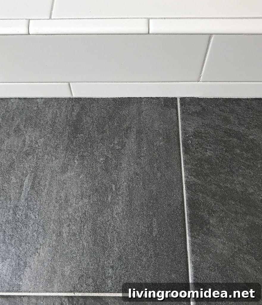 white subway tile shower next to dark slate floor with same gray grout