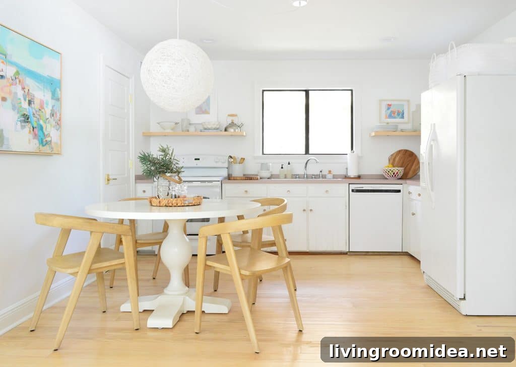 Minimal Kitchen With White Cabinets Pedestal Table And Globe Pendant Light With Wood Chairs