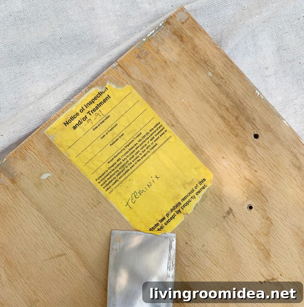 Scraping old label off the back of kitchen cabinets as painting prep
