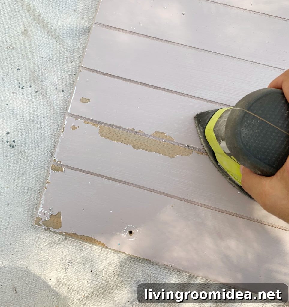Sanding old paint drips off of wood cabinets in preparation for cabinet painting