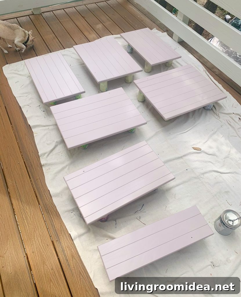 Wood cabinet doors on drop cloth drying with coat of mauve paint 