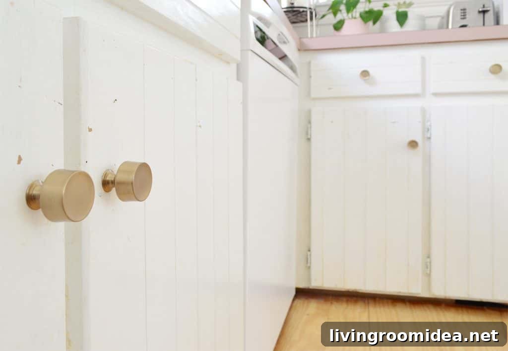 Close up before photo of white cabinets with paint flecks near knobs