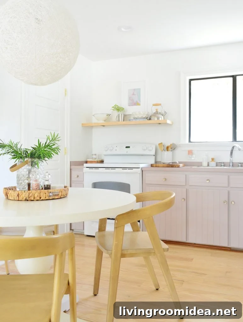 Simple white kitchen with mauve Artsy Pink cabinets and pedestal table