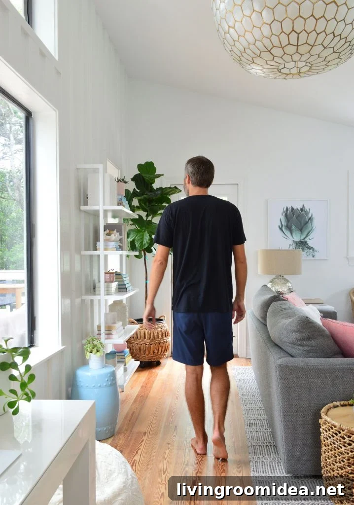 Man In Black Shirt Walking In Living Room Under Large Light Fixture